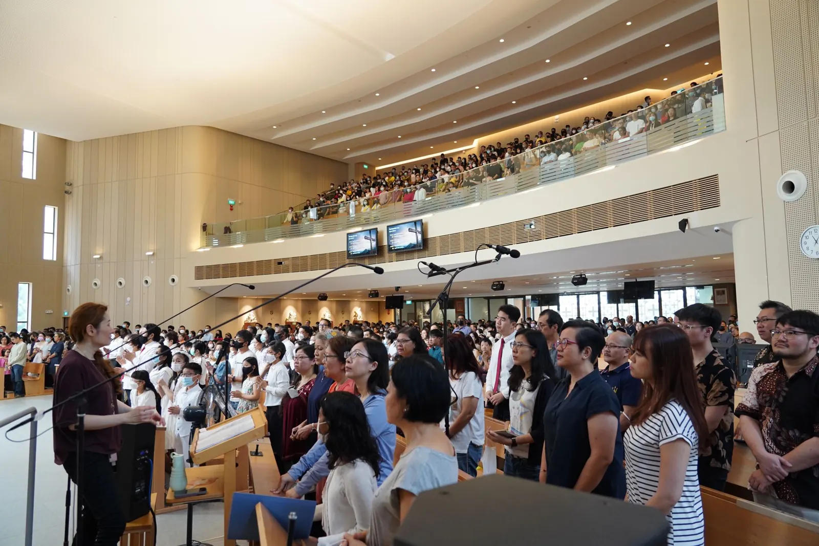 A cantor at the microphone leading a full church in song during Mass